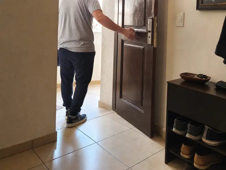Persona saliendo por la puerta de un apartamento sin mostrar el rostro